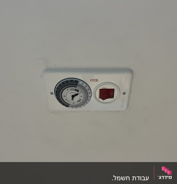 שעון טיימר ומתג חשמלי על קיר לבן